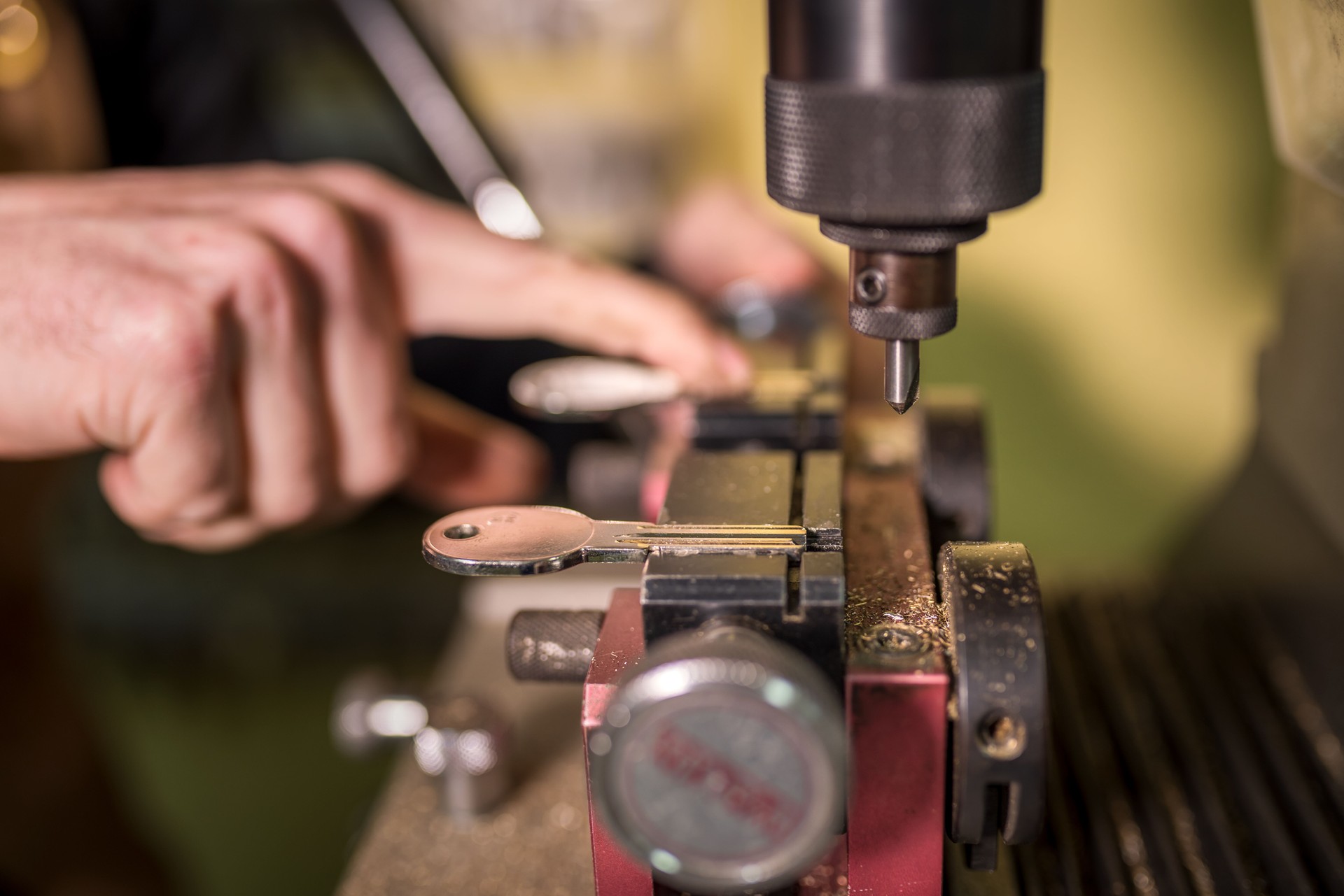 Key duplication process, specialized machine copying metal key with professional precision, metallic mechanical workshop setting